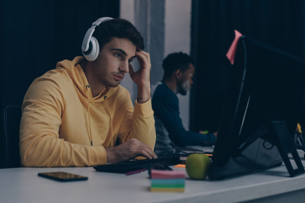 Programmoer koncentrerer sig med hoeretelefoner paa foran sin computer