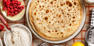 Pandekager paa bord med friske baer og sukker