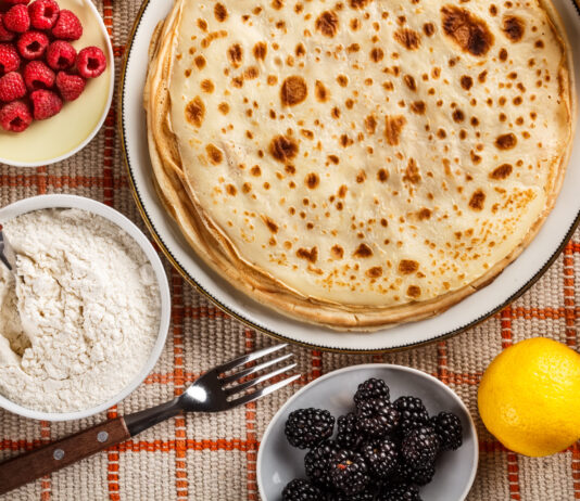 Pandekager paa bord med friske baer og sukker